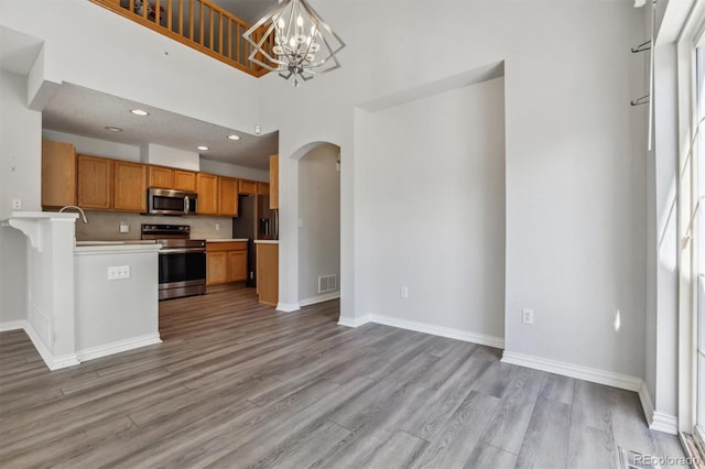 kitchen featuring hanging light fixtures, light hardwood / wood-style flooring, stainless steel appliances, and a chandelier