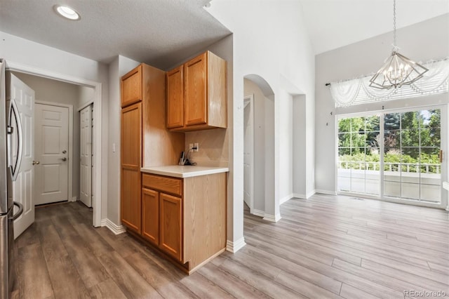 kitchen featuring a textured ceiling, hanging light fixtures, wood-type flooring, and a notable chandelier