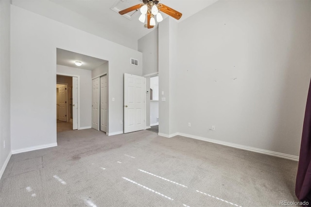 unfurnished bedroom featuring a high ceiling, ceiling fan, and light colored carpet