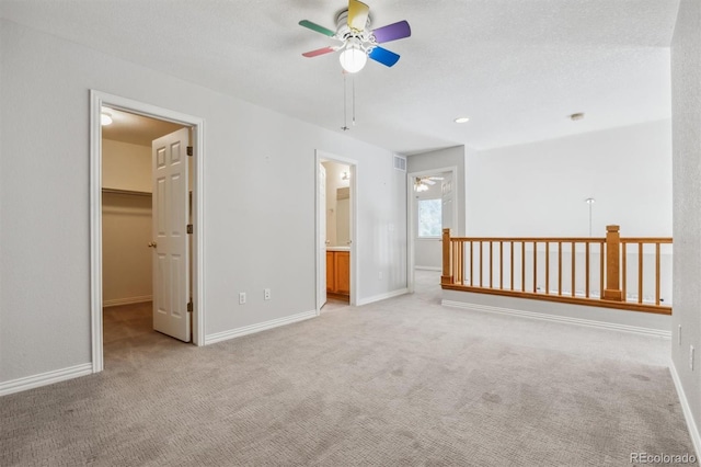 empty room with ceiling fan, light colored carpet, and a textured ceiling