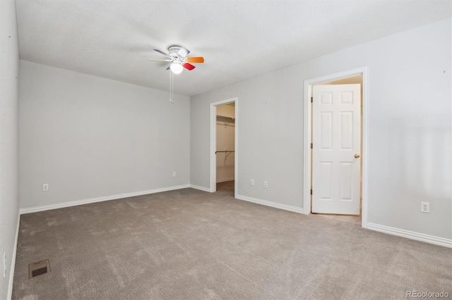 unfurnished bedroom with a spacious closet, ceiling fan, and light colored carpet