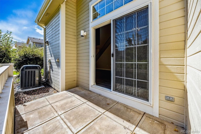 view of exterior entry with a patio and central AC unit