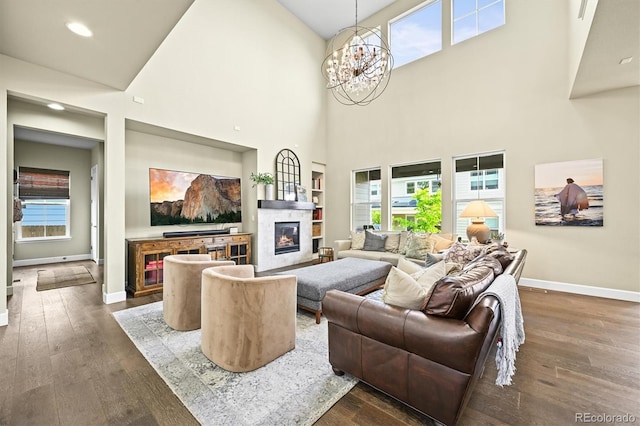 15033 Delhi Ave, Parker, CO 80134 - living area with a glass covered fireplace, baseboards, dark wood-type flooring, a chandelier, and a towering ceiling