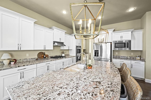 15033 Delhi Ave, Parker, CO 80134 - kitchen featuring appliances with stainless steel finishes, a large island with sink, a sink, white cabinets, and recessed lighting