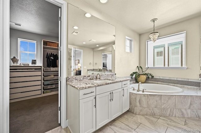15033 Delhi Ave, Parker, CO 80134 - full bath featuring vanity, a bath, marble look tiles, a walk in closet, and a textured ceiling