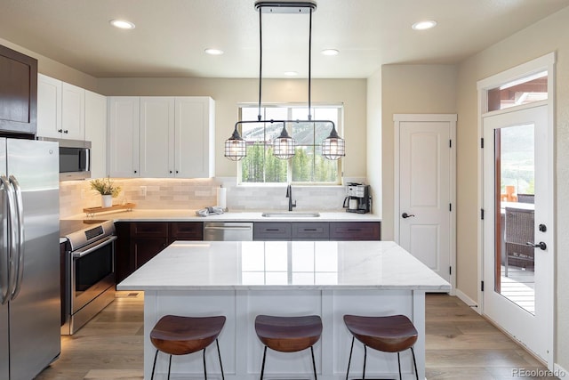 327 Summit Lift Ct, Granby, CO 80446 - kitchen with stainless steel appliances, a sink, tasteful backsplash, a kitchen breakfast bar, and light wood-type flooring