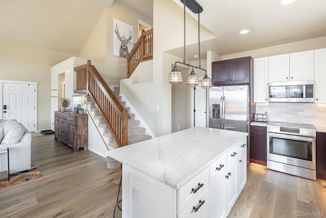 327 Summit Lift Ct, Granby, CO 80446 - kitchen featuring stainless steel appliances, open floor plan, light wood-type flooring, a breakfast bar area, and decorative backsplash
