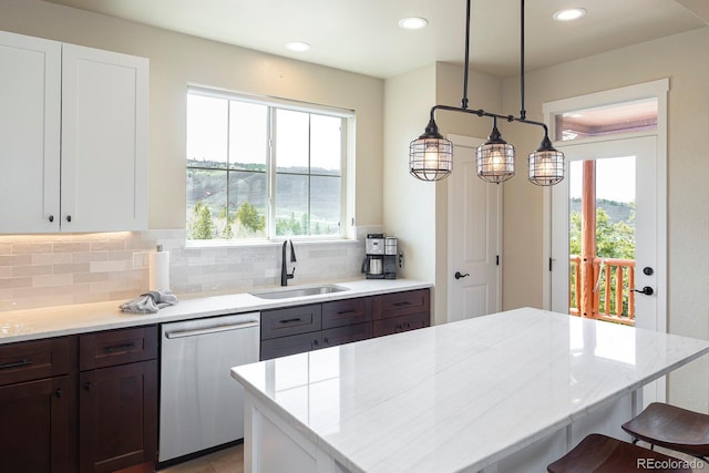 327 Summit Lift Ct, Granby, CO 80446 - kitchen featuring stainless steel dishwasher, a sink, a kitchen bar, tasteful backsplash, and light stone countertops