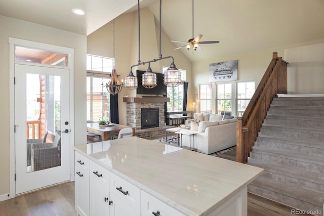 327 Summit Lift Ct, Granby, CO 80446 - kitchen featuring light wood finished floors, a ceiling fan, a fireplace, open floor plan, and high vaulted ceiling