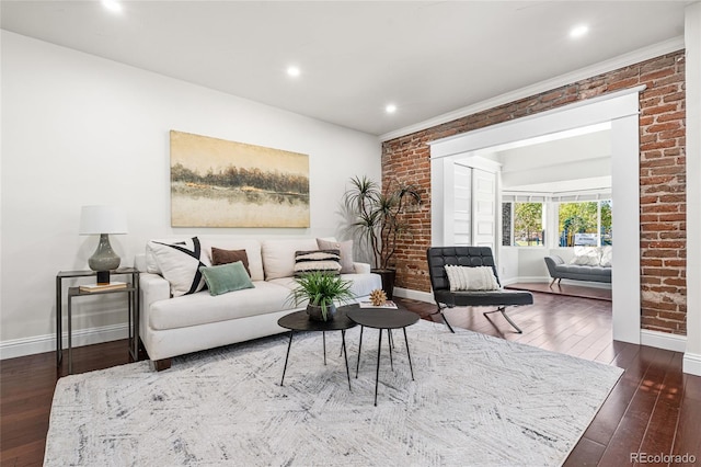 living area featuring baseboards, hardwood / wood-style floors, recessed lighting, and brick wall