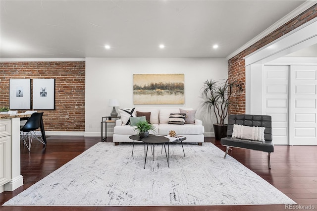 living area featuring brick wall, dark wood-type flooring, baseboards, recessed lighting, and crown molding