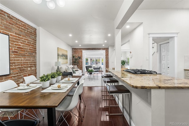 dining space with brick wall, dark wood-style floors, and recessed lighting