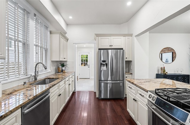 kitchen with appliances with stainless steel finishes, a sink, light stone countertops, tasteful backsplash, and recessed lighting