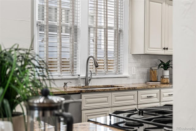 kitchen with a sink, tasteful backsplash, stone countertops, white cabinets, and gas cooktop