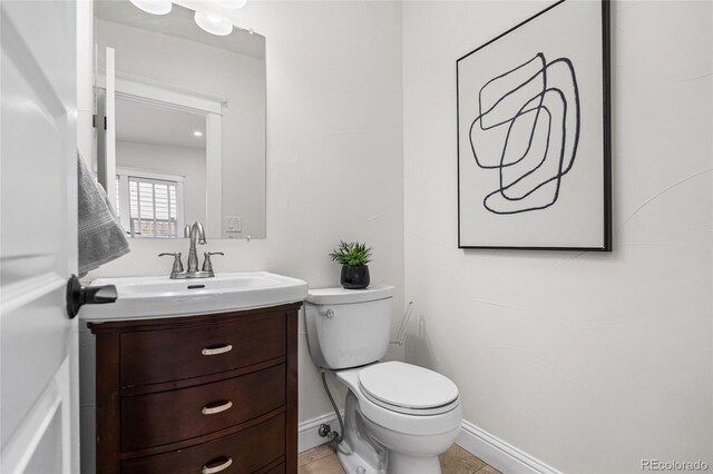 bathroom with vanity, toilet, and baseboards