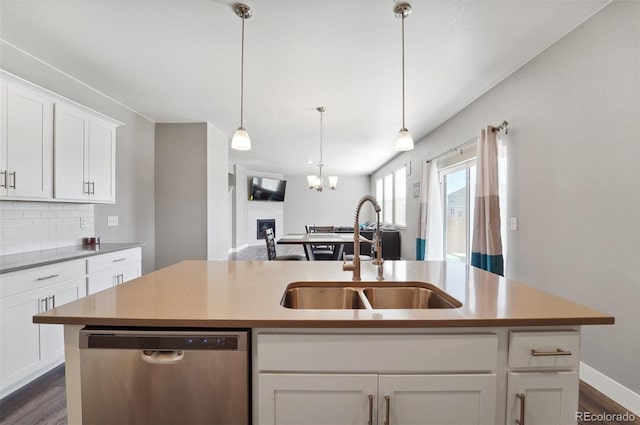 2128 Dexter St, Mead, CO 80542 - kitchen featuring stainless steel dishwasher, tasteful backsplash, dark wood-type flooring, white cabinetry, and a center island with sink