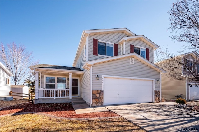 traditional-style home with covered porch, driveway, stone siding, and a garage