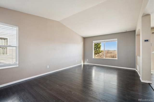 empty room with dark wood-style floors, baseboards, and vaulted ceiling