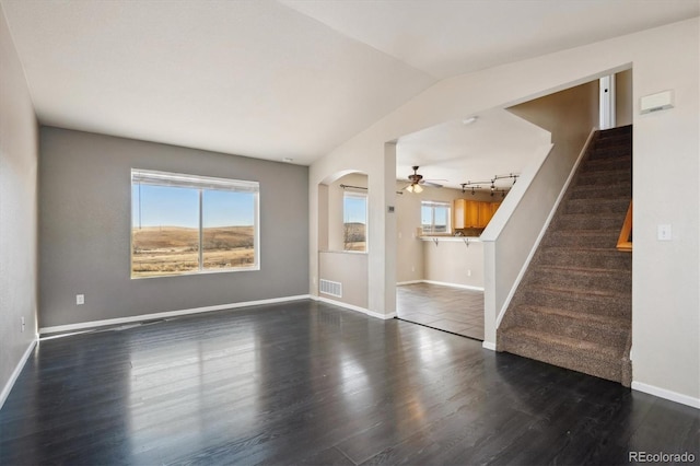 unfurnished living room featuring visible vents, vaulted ceiling, wood finished floors, baseboards, and stairs