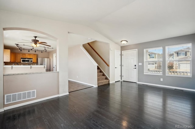 unfurnished living room featuring visible vents, a ceiling fan, lofted ceiling, wood finished floors, and stairs