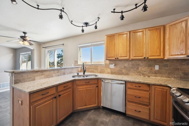 kitchen with a peninsula, plenty of natural light, stainless steel appliances, and a sink