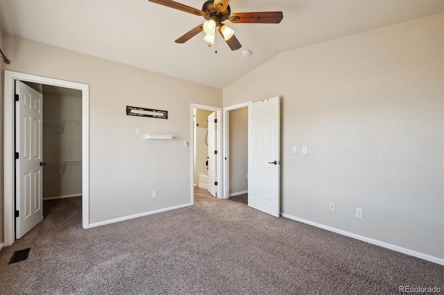 unfurnished bedroom featuring carpet flooring, visible vents, baseboards, vaulted ceiling, and a spacious closet