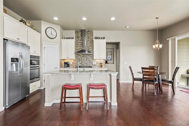 kitchen with dark hardwood / wood-style flooring, appliances with stainless steel finishes, a kitchen island with sink, white cabinetry, and wall chimney range hood