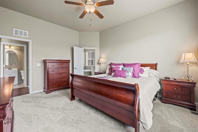 bedroom featuring ensuite bath, light colored carpet, and ceiling fan