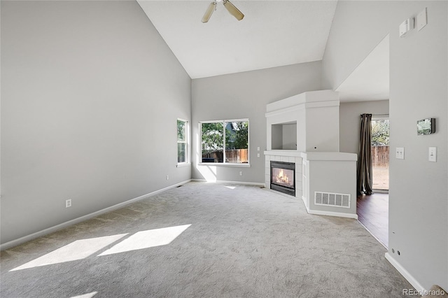 unfurnished living room with light carpet, plenty of natural light, and a tiled fireplace