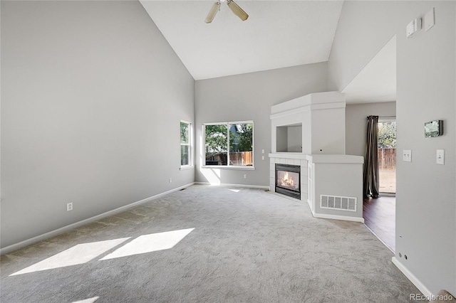 19873 E Vassar Ave, Aurora, CO 80013 - unfurnished living room with high vaulted ceiling, healthy amount of natural light, baseboards, carpet flooring, and a tiled fireplace