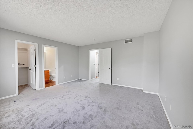 19873 E Vassar Ave, Aurora, CO 80013 - unfurnished bedroom featuring a spacious closet, light carpet, a textured ceiling, and baseboards