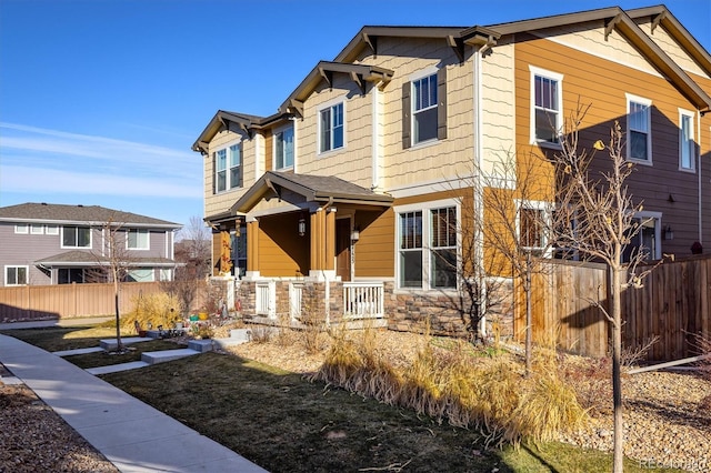 craftsman-style house with stone siding and fence