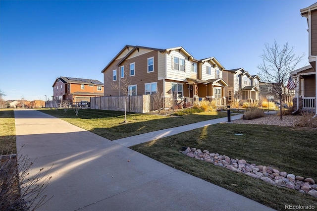 view of front of house with a residential view, fence, and a front lawn