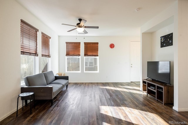 living area featuring dark wood finished floors, baseboards, and ceiling fan