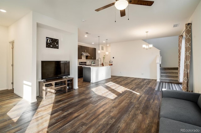 living area featuring stairs, dark wood-style flooring, recessed lighting, visible vents, and ceiling fan with notable chandelier