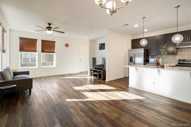 kitchen featuring appliances with stainless steel finishes, a kitchen breakfast bar, open floor plan, light countertops, and under cabinet range hood