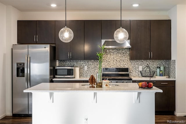 kitchen featuring appliances with stainless steel finishes, a kitchen breakfast bar, hanging light fixtures, and ventilation hood