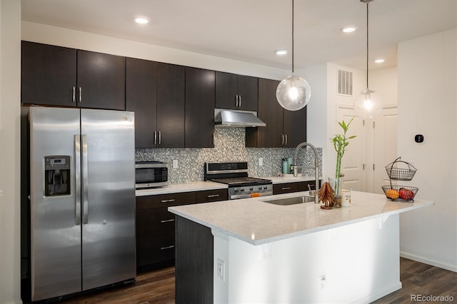 kitchen featuring dark brown cabinetry, under cabinet range hood, stainless steel appliances, visible vents, and pendant lighting