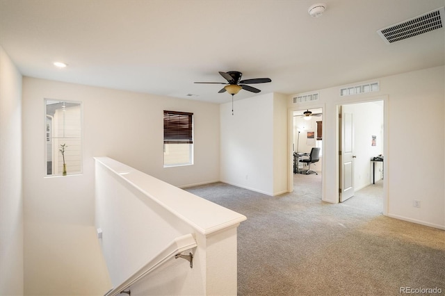 corridor featuring light carpet, baseboards, and visible vents