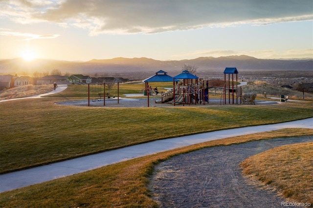 playground at dusk with playground community, a yard, and a mountain view