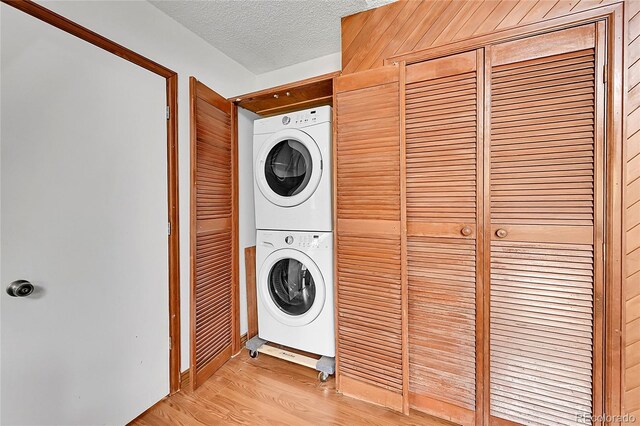 101 Campbell Rd, Bailey, CO 80421 - laundry area featuring stacked washer / drying machine, light wood-type flooring, and a textured ceiling