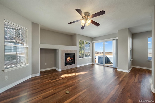 unfurnished living room featuring a water view, ceiling fan, a textured ceiling, a fireplace, and dark hardwood / wood-style flooring