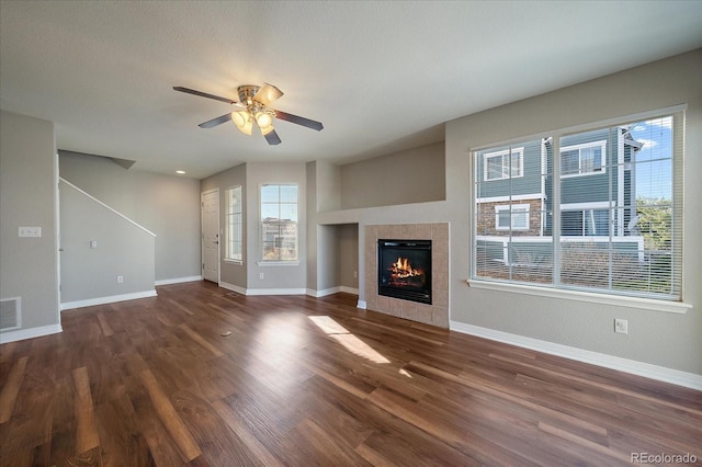 unfurnished living room featuring ceiling fan, a fireplace, dark wood-type flooring, and a textured ceiling