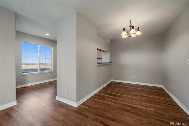 unfurnished room with a chandelier and dark hardwood / wood-style flooring