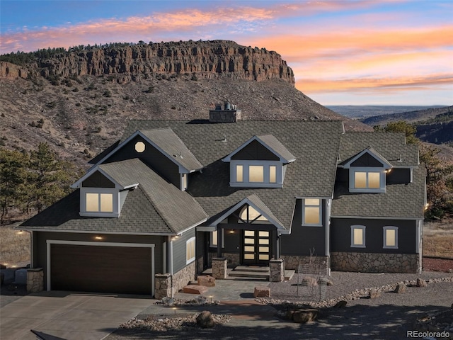 view of front facade with a garage, stone siding, driveway, and a shingled roof