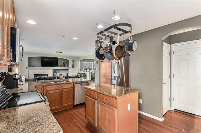 kitchen featuring arched walkways, dark wood finished floors, stainless steel appliances, and a sink