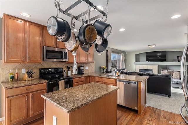 kitchen featuring brown cabinets, appliances with stainless steel finishes, a center island, and a peninsula