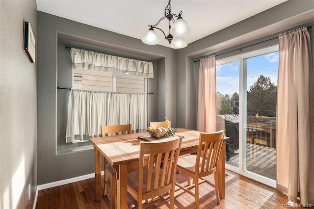 dining space featuring a chandelier, baseboards, and wood finished floors