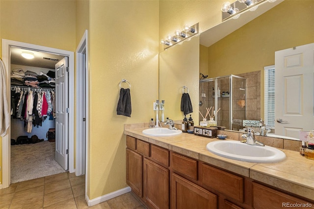 bathroom featuring a walk in closet, tile patterned floors, a stall shower, and a sink