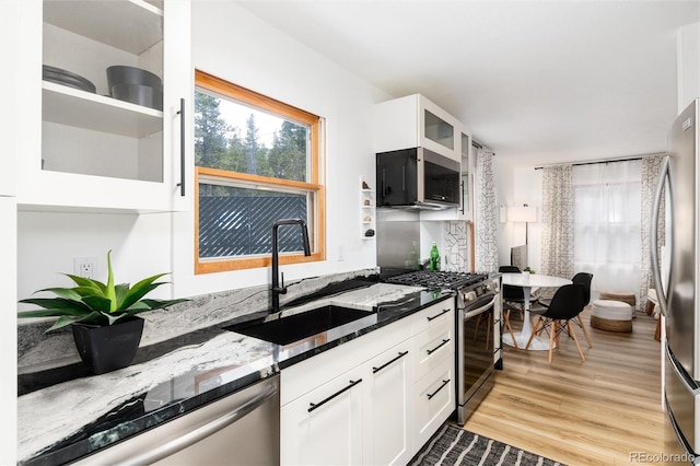 236 Harris Dr, Idaho Springs, CO 80452 - kitchen featuring appliances with stainless steel finishes, a sink, dark stone counters, light wood finished floors, and white cabinets